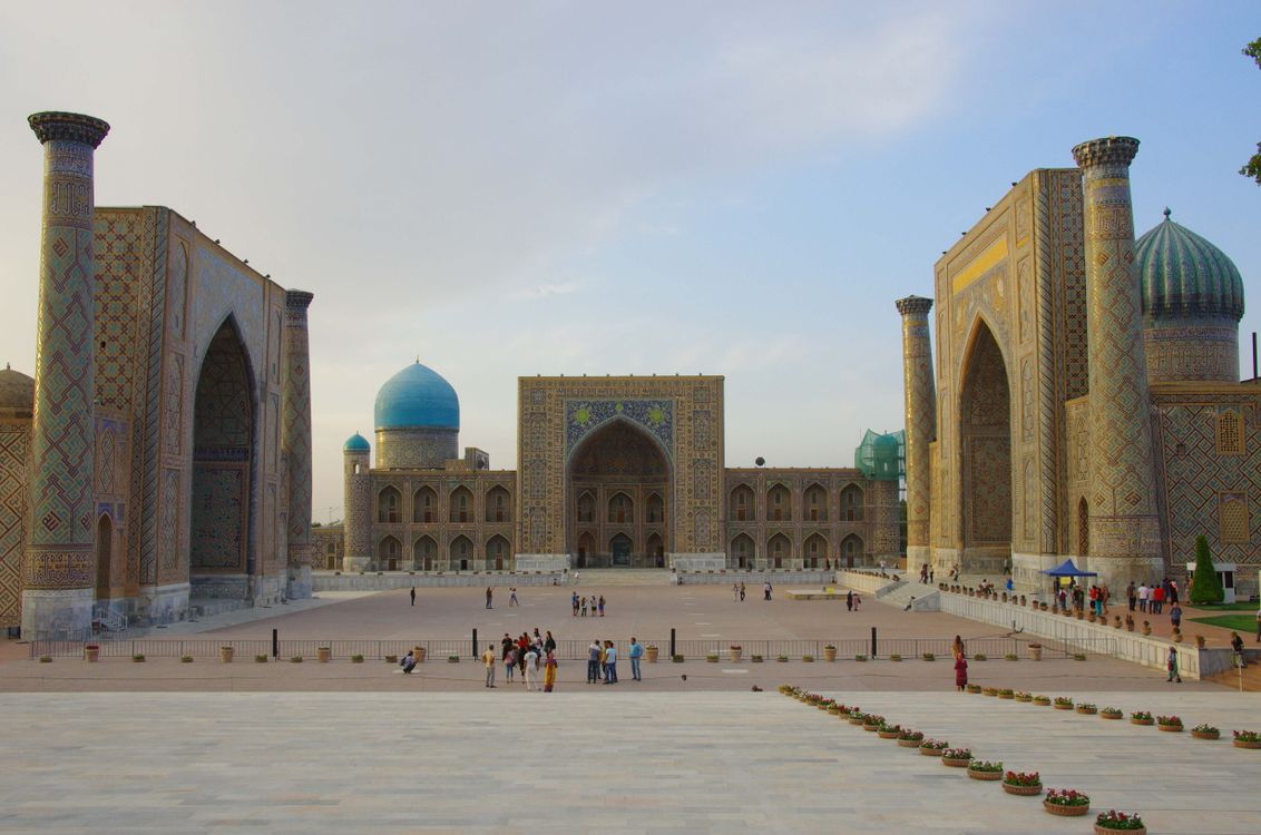 The Registan Square in Samarkand, Uzbekistan, three ornate madrasahs with blue-tiled domes under a clear sky