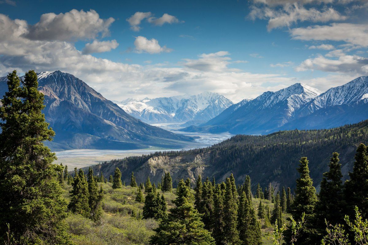 A still alpine lake ringed by green mountain slopes under a wide sky